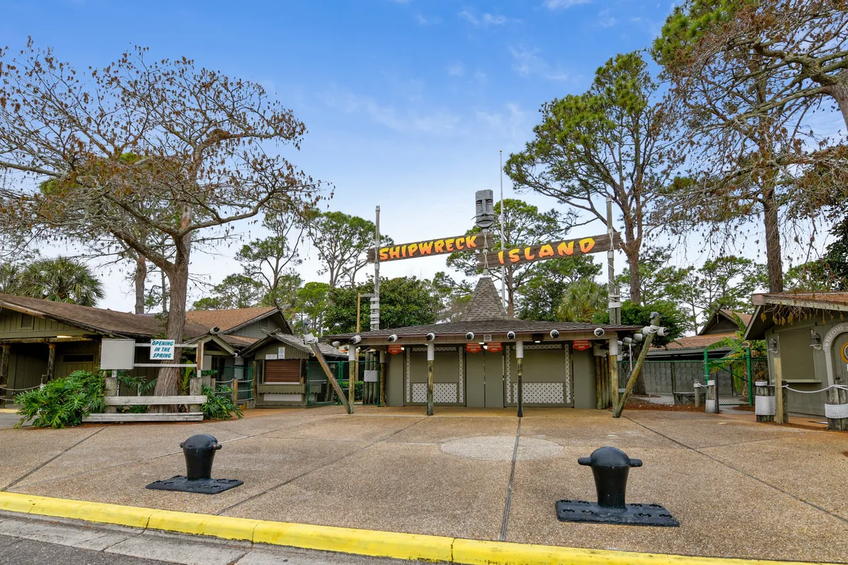 Vivid exterior shot featuring the Shipwreck Island Water Park entrance, complete with the recognizable sign and lush, inviting landscaping. The park’s entrance hints at the thrilling water attractions and adventures that await families, highlighting one of the complimentary local experiences offered to guests.
